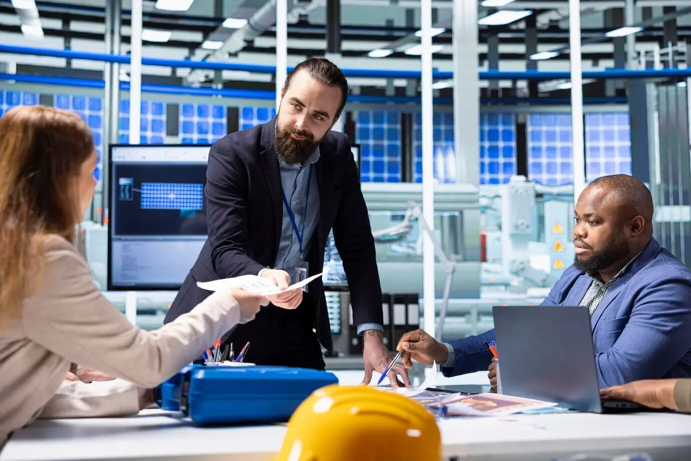 Менеджер завода передает документы инвесторам, изучающим финансовую отчетность.